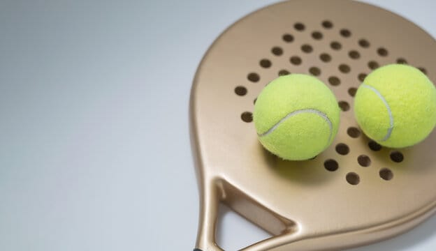 a paddle racket with two balls on a white background.